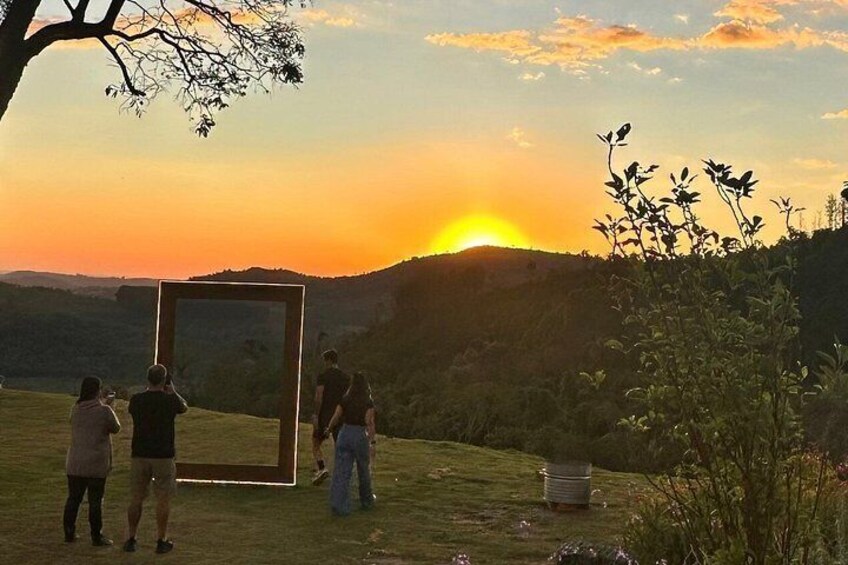 A sunset with a group of people standing in a grassy field, holding a large mirror. 3