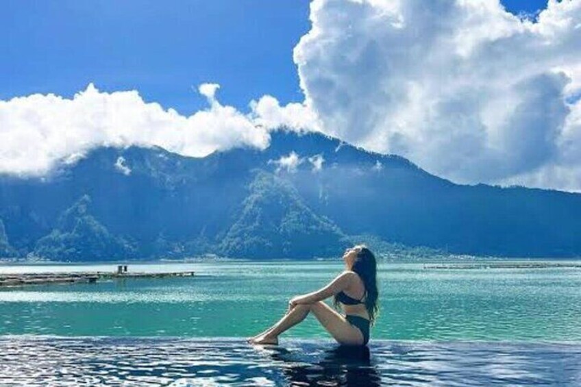 A person sitting by a pool with a mountainous landscape in the background. 1