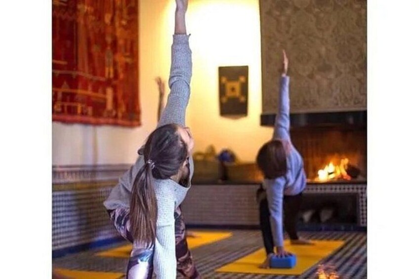 Twee personen doen yoga in een kamer met een open haard. 1