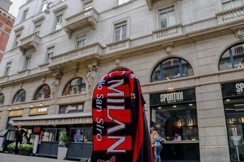 A red and black sign with the word 'MILAN' on a building facade. 5