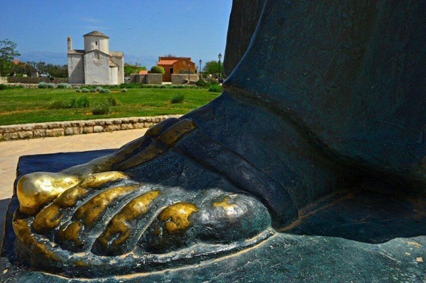 A close-up of a statue's foot with a golden shoe. 3