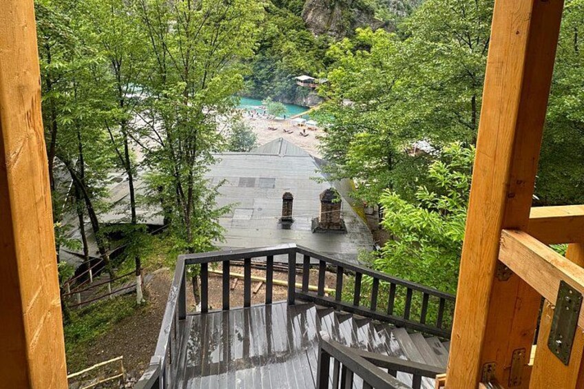Un escalier en bois mène à un espace piscine entouré d’arbres. 3