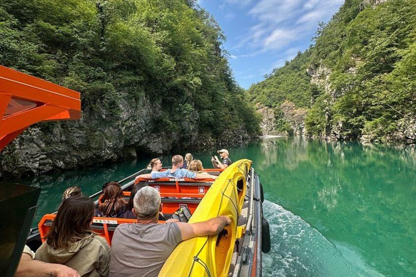 Een groep mensen op een boot in een rivier, omringd door steile kliffen. 2