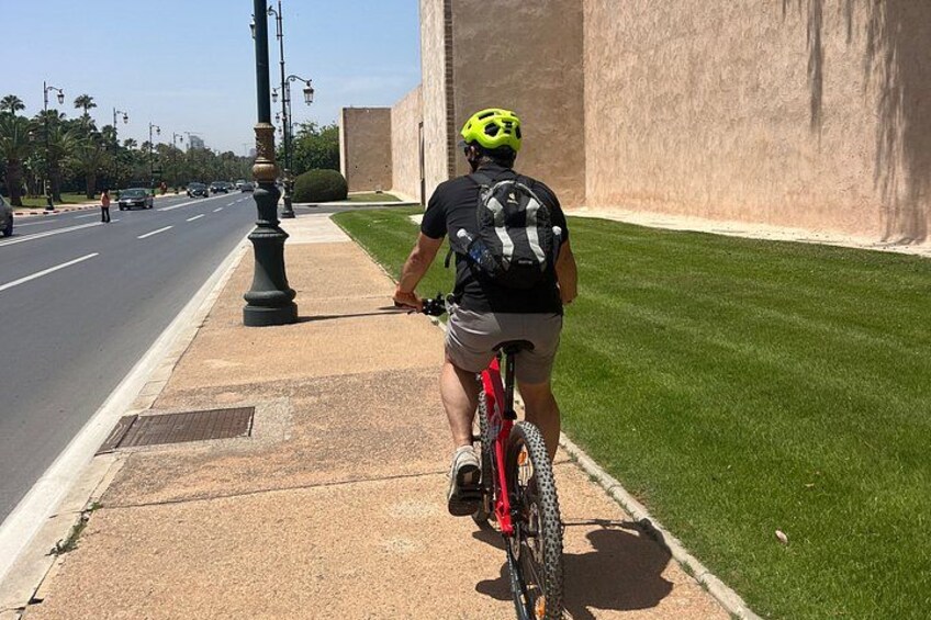 A person riding a bicycle on a sidewalk next to a road. 5