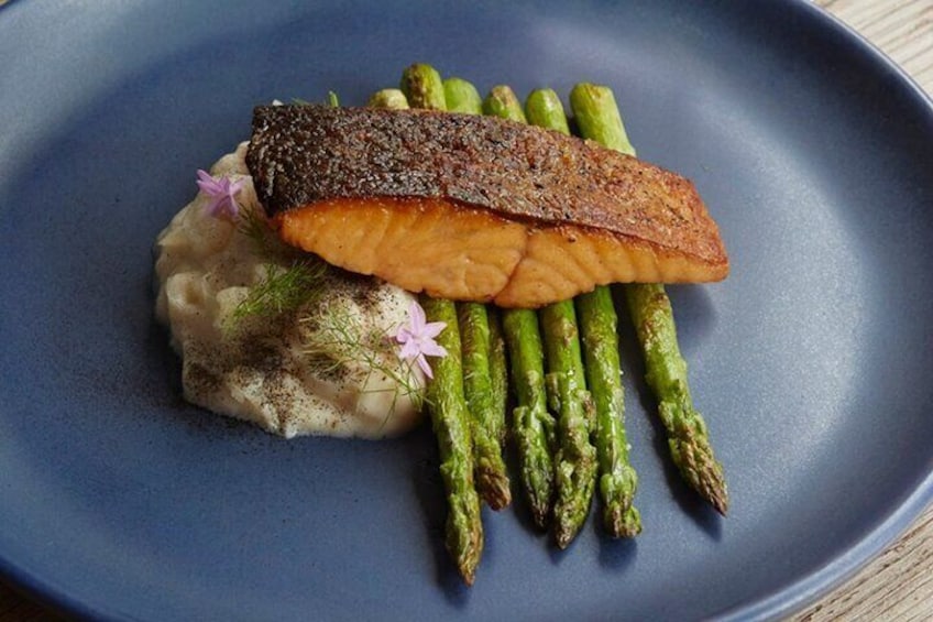 A plate with grilled salmon, asparagus, and a creamy side dish. 1