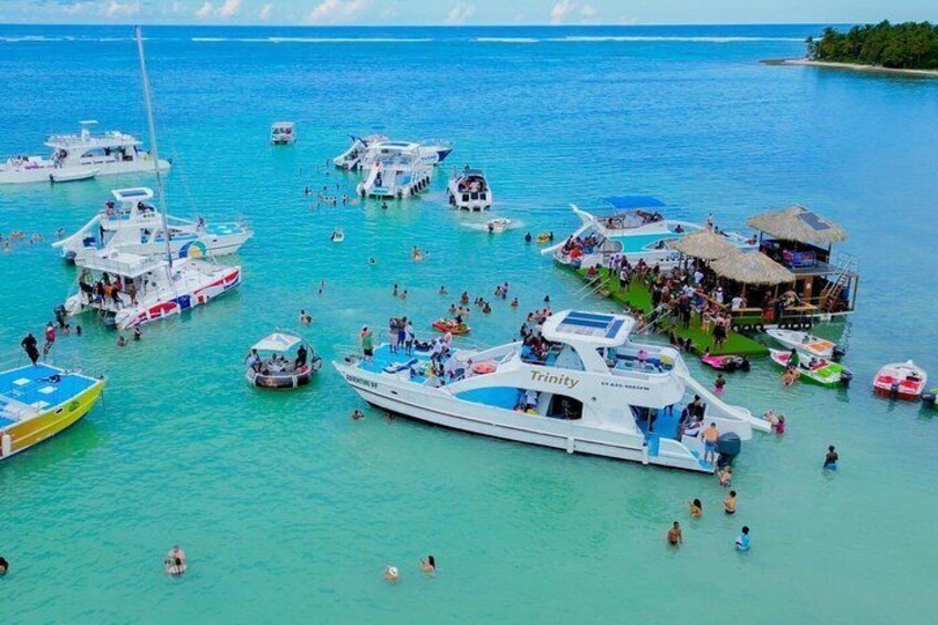 A marina with multiple boats, people swimming, and a dock with a thatched-roof structure. 2