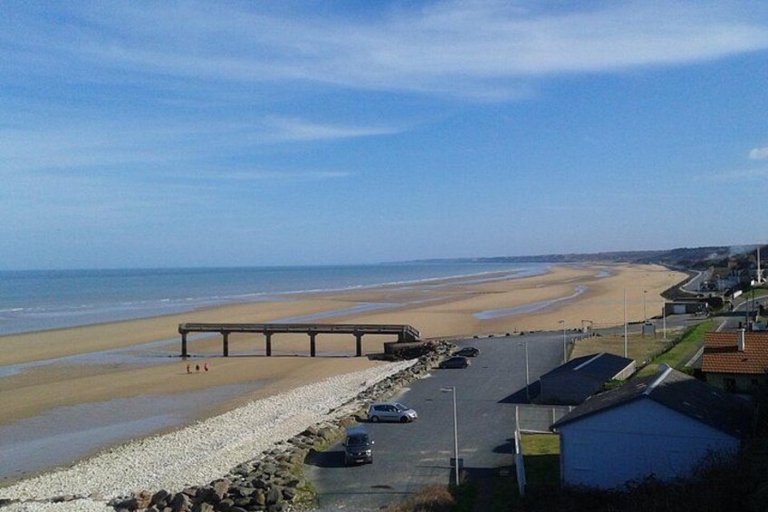 A beach with a wooden pier, a parking lot, and a residential area. 2