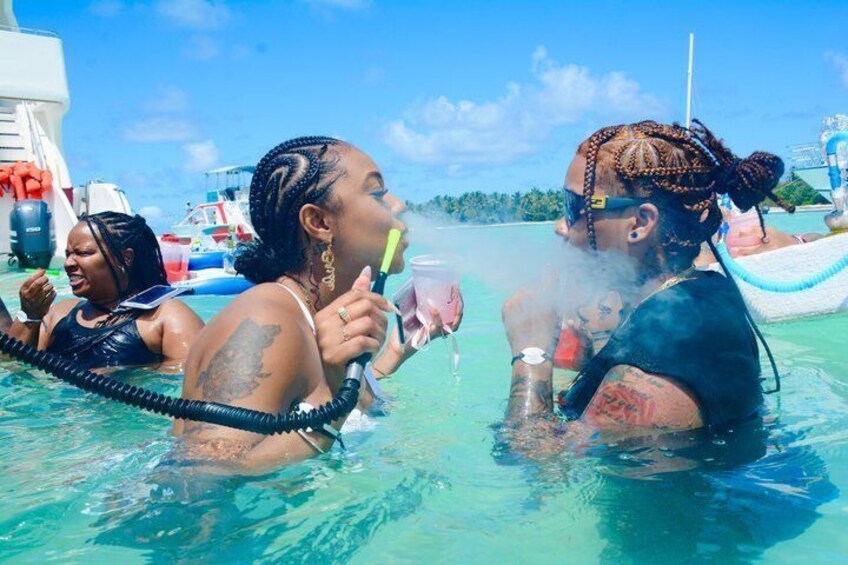 People in a clear blue sea, some with snorkels, on a boat. 2