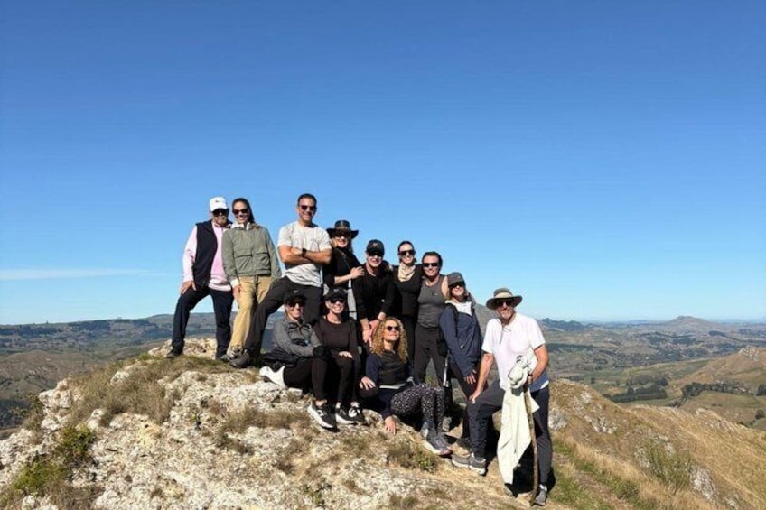 A group of people on a rocky outcrop with a mountainous landscape in the background. 1