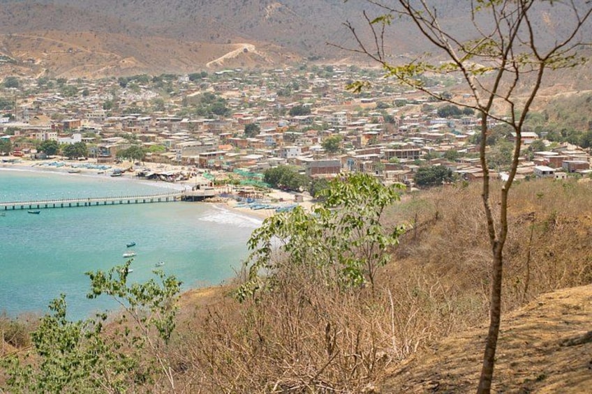A coastal town with a pier extending into the sea, surrounded by hills and sparse vegetation. 3