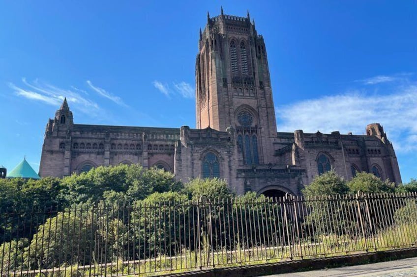 A large cathedral with a tall tower, surrounded by a fence and greenery. 3