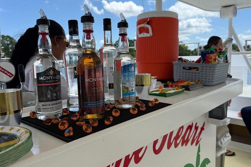 A bar area on a boat with various liquor bottles, a red cooler, and a white counter with 'Viva Uva' written on it. 2