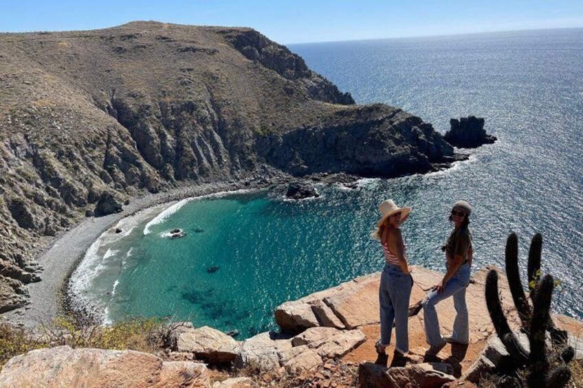 A coastal landscape with a rocky shoreline, clear turquoise waters, and a distant view of the ocean. 1