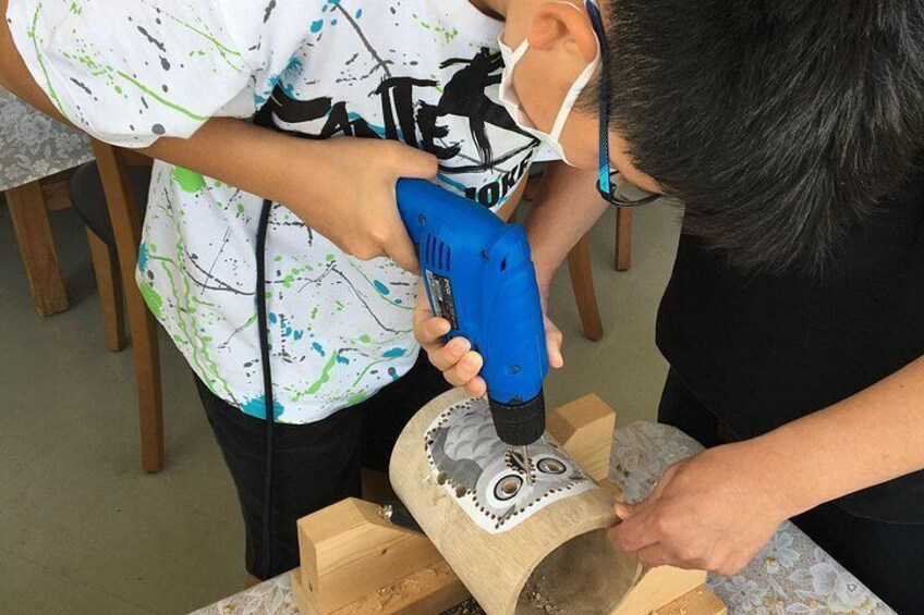 A person using a blue power tool on a wooden object. 5