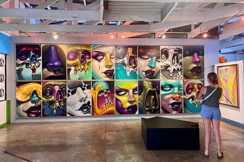 An art gallery with a large mural of colorful faces on the wall. 5
