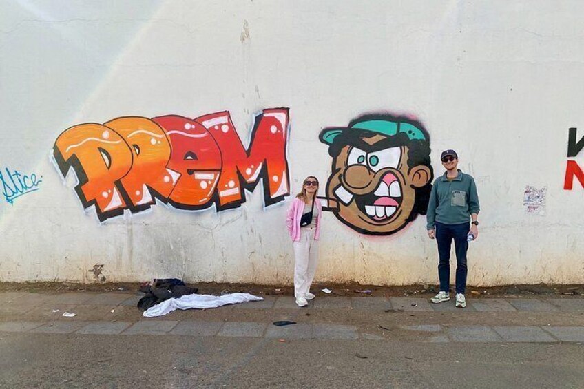 A street with a large graffiti wall featuring the word 'PREM' and a cartoon character. 2