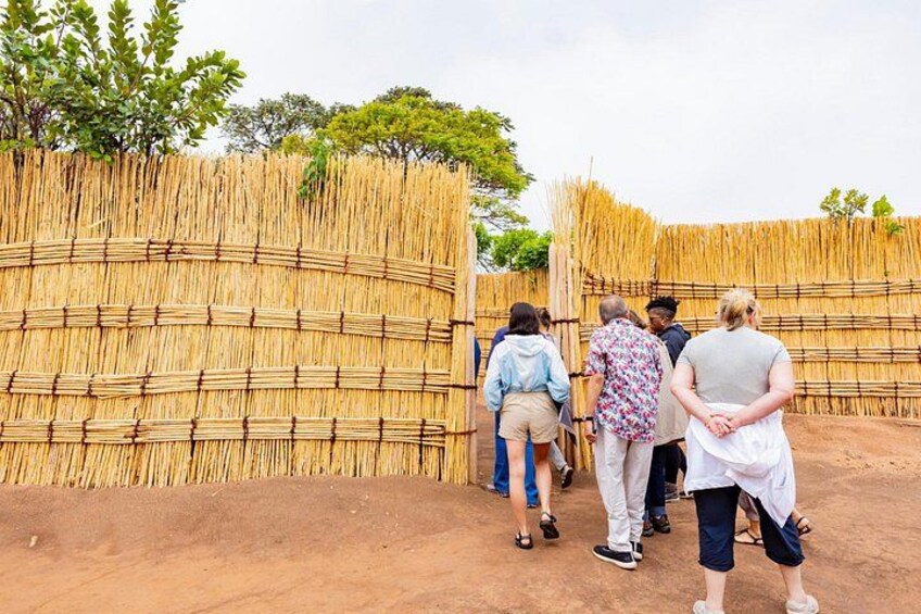 A group of people walking past a bamboo fence in a natural setting. 5