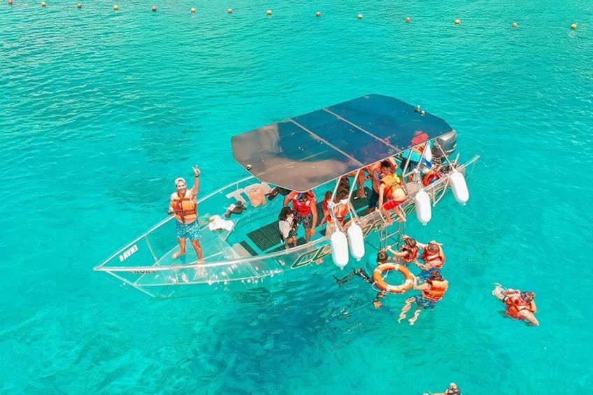 A boat with people on a turquoise sea, some wearing life jackets. 1
