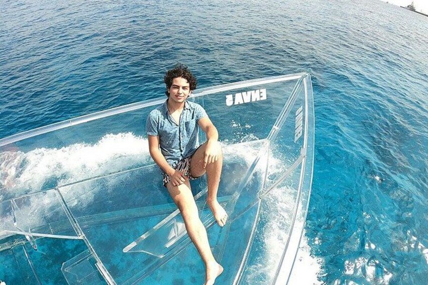 A person sitting on a transparent boat in a body of water. 3
