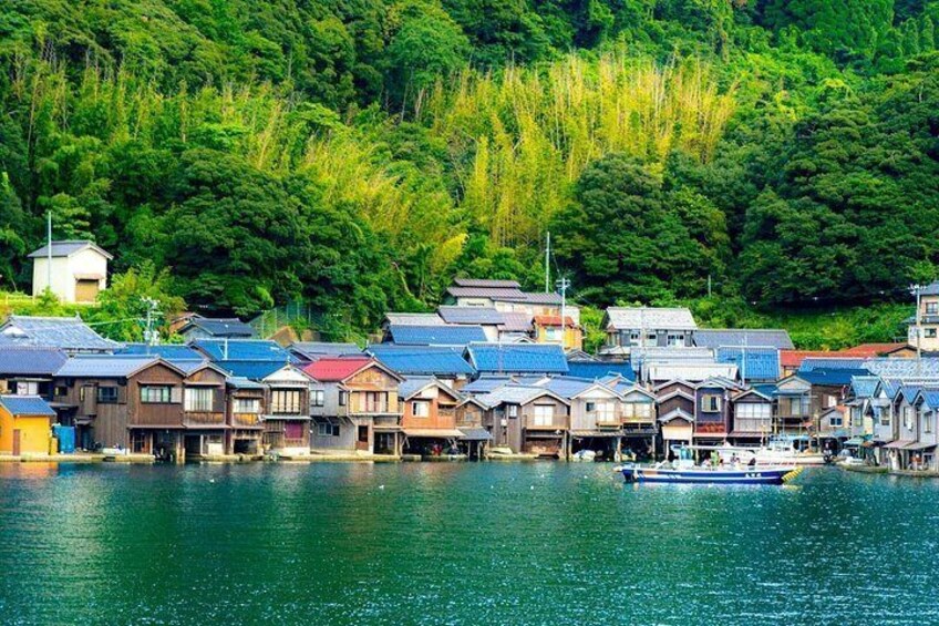 A coastal village with traditional houses, a boat on the water, and dense forest in the background. 3