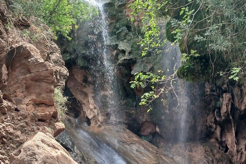 A waterfall cascading down a rocky cliff surrounded by greenery. 3
