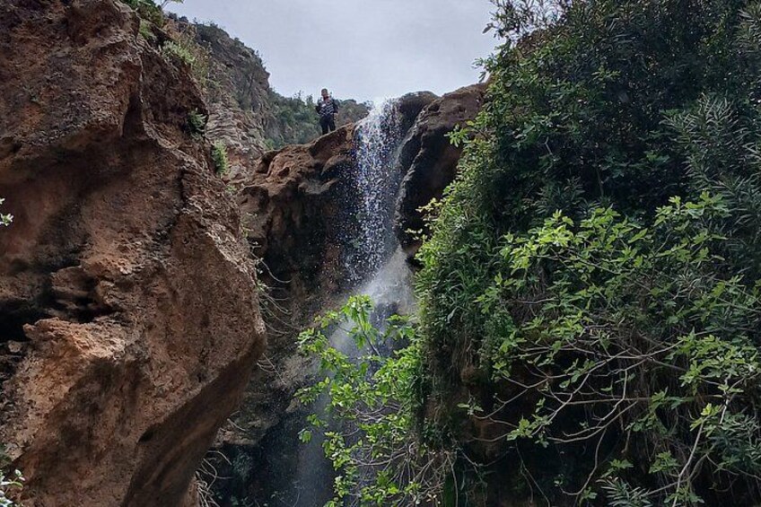 A waterfall cascading down a rocky cliff surrounded by lush greenery. 4