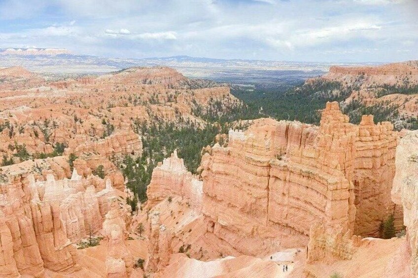 A canyon with layered rock formations and a distant cityscape. 2