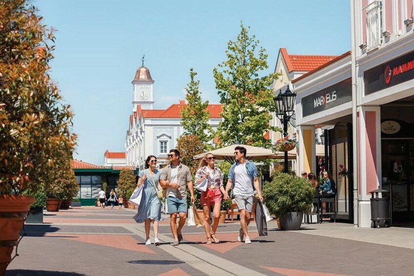 A pedestrian street with shops, a clock tower, and people walking. 4