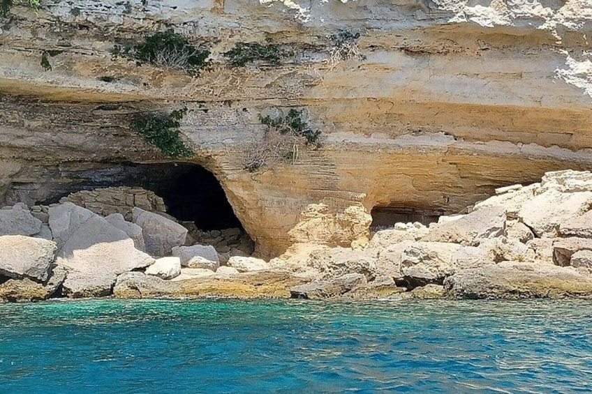 Entrada de una cueva costera rodeada de rocas y agua azul cristalina. 4