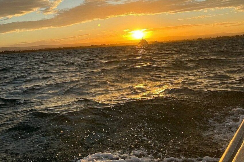 Atardecer sobre el océano con olas y un barco en primer plano. 3