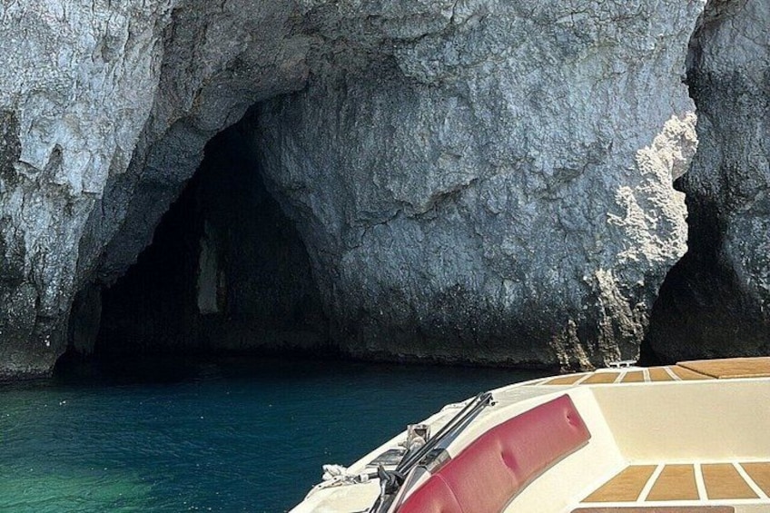 Un bote cerca de la entrada de una cueva rocosa con agua azul cristalina. 1