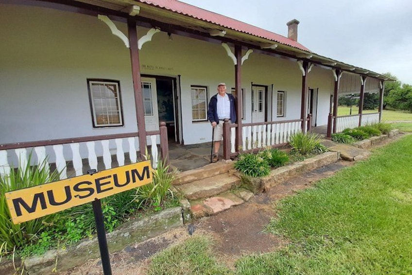 A museum with a porch, a person standing, and a sign. 3