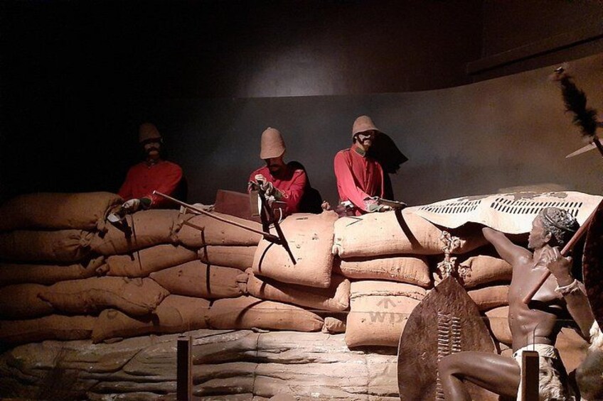 A historical reenactment with figures in period costumes, a large pile of sacks, and a feathered headdress. 5