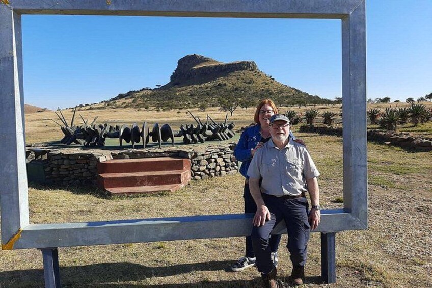 A person standing in front of a metal frame with a landscape in the background. 1