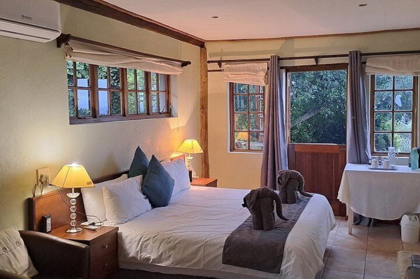 A bedroom with a large bed, two bedside lamps, a nightstand, a window with curtains, and a small table with a lamp. 3