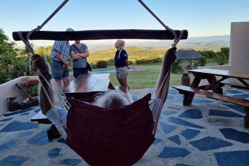 A hammock suspended over a patio with a scenic view, a wooden table, and a stone-tiled floor. 2
