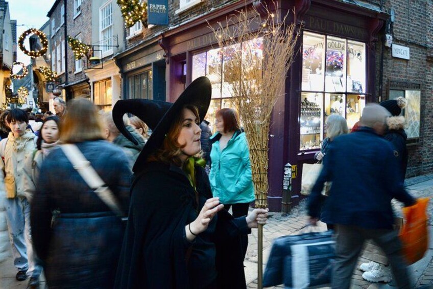 A busy street with people walking, a shop with a purple facade, and a Christmas tree. 4