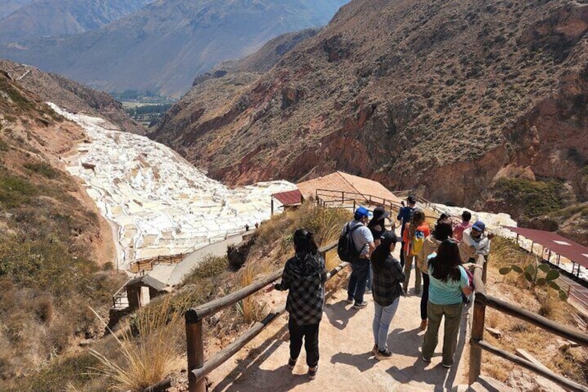 A group of hikers on a dirt path with a view of a glacier in the valley. 4