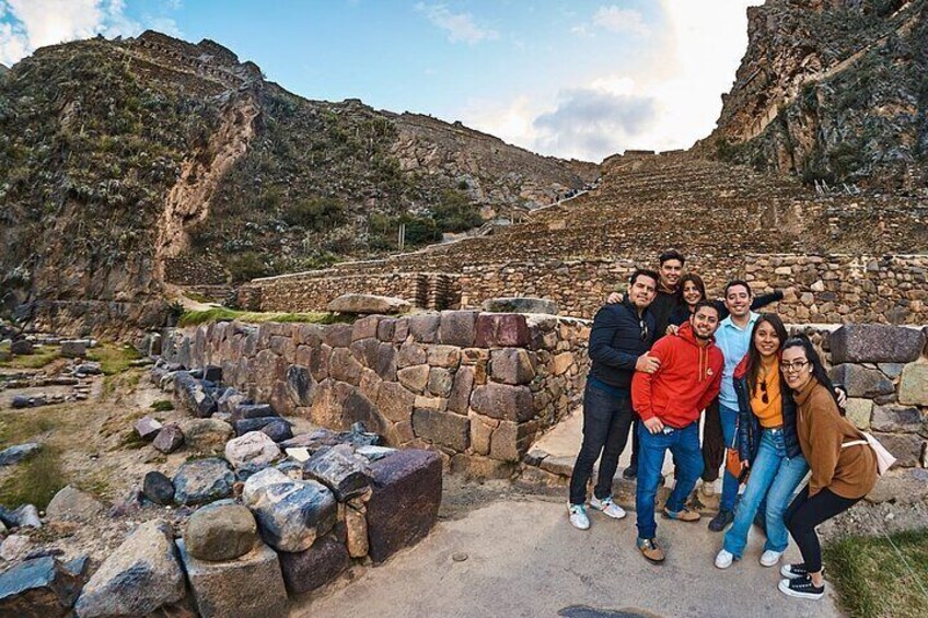 A group of people standing in front of ancient stone ruins with a mountainous backdrop. 3