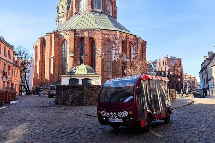 A red van parked on a cobblestone street in front of a historic church with a dome. 4