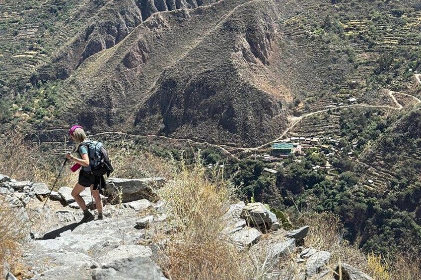 A hiker on a rocky path with a mountainous landscape in the background. 3