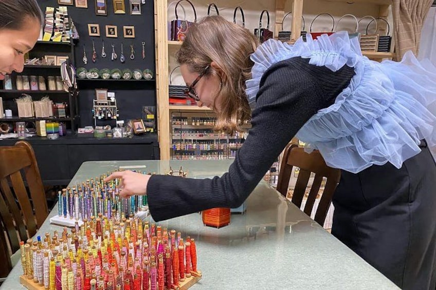 A person arranging colorful bottles on a table in a shop with shelves of various items in the background. 2