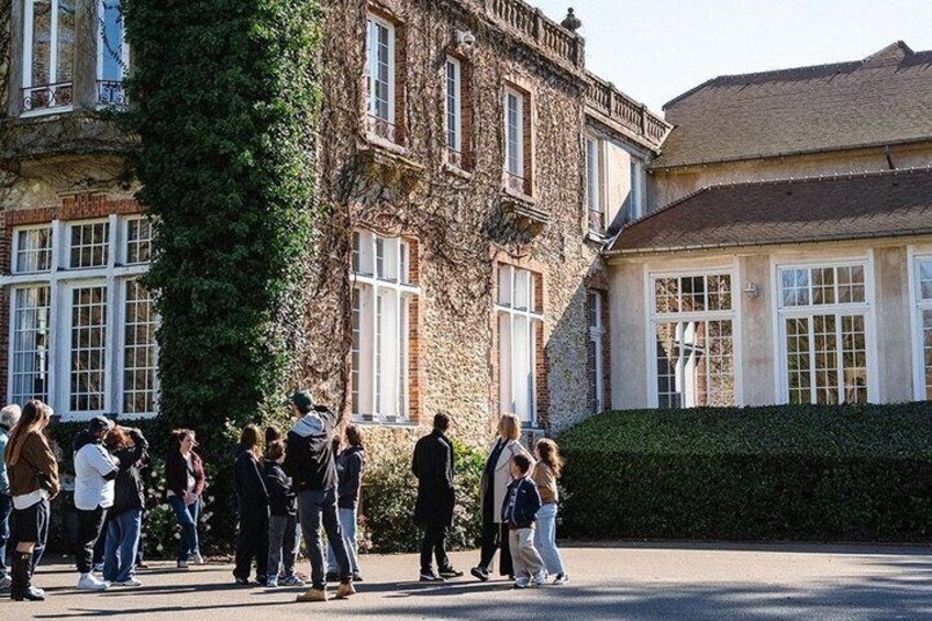 A group of people standing in front of a building with ivy-covered walls and large windows. 3