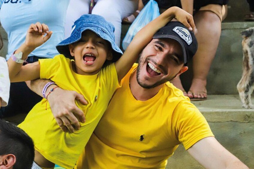 A person wearing a yellow shirt and a blue hat, sitting on steps with a dog. 5