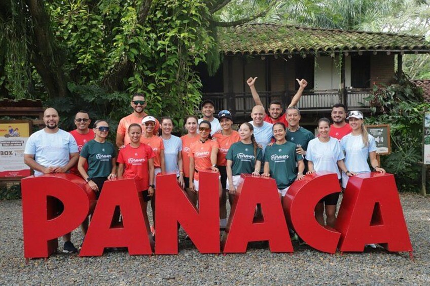 A group of people standing in front of large red letters spelling 'PANACA'. 1