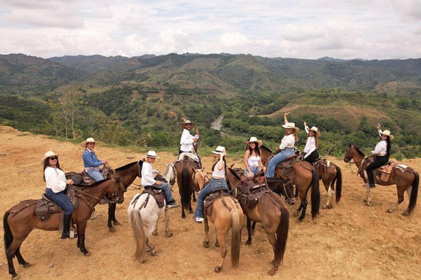 A group of people riding horses on a dirt path with a mountainous landscape in the background. 4