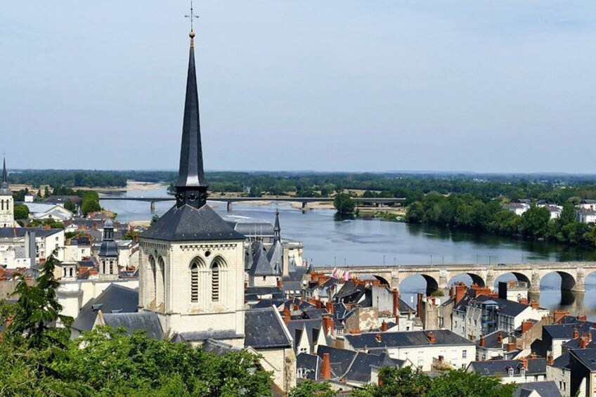 A river with a bridge, a church with a tall spire, and a cityscape with buildings. 2