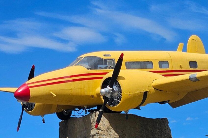 A yellow propeller-driven aircraft with red stripes, parked on a wooden structure. 3