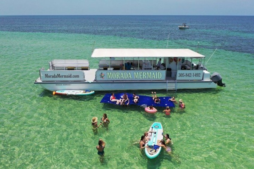 A boat named 'Morada Mermaid' with people swimming and floating on the water. 1