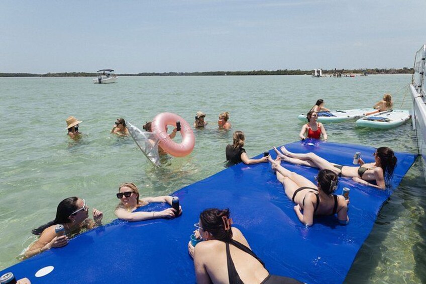 Menschen auf einer schwimmenden Plattform im Wasser, manche halten Luftmatratzen. 2